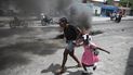 Una mujer y una niña corren junto a una fogata durante una manifestación contra la violencia en Puerto Príncipe, Haití, el 29 de marzo del 2022. 