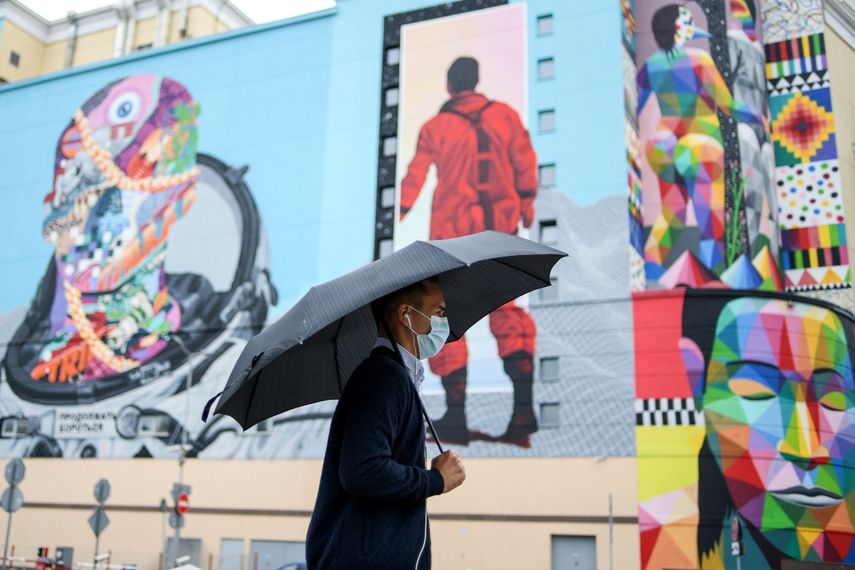 Un hombre que usa una mascarilla para protegerse contra la enfermedad del coronavirus camina con un paraguas bajo una lluvia ligera en el centro de Mosc&uacute; el 13 de agosto de 2020