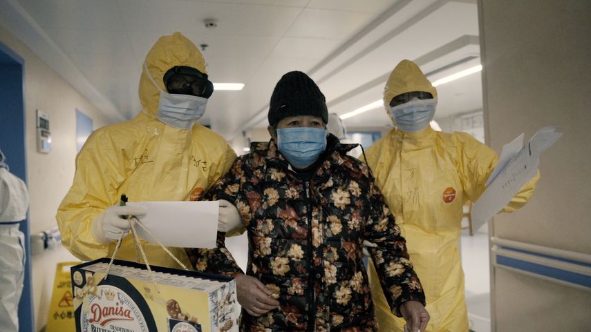 Una mujer mayor con COVID-19, centro, es acompañada por dos enfermeras tras ser admitida en un hospital en Wuhan, China, en una escena del documental 76 Days. El filme realizado en hospitales de Wuhan captura el horror local antes de que se volviera una pesadilla mundial.