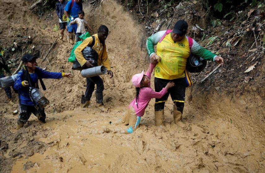  Una mujer trata de levantar a una niña de un paso enlodado mientras migrantes ecuatorianos atraviesan la selva del Darién para llegar desde Colombia a Panamá en su ruta hacia Estados Unidos, el 15 de octubre de 2022