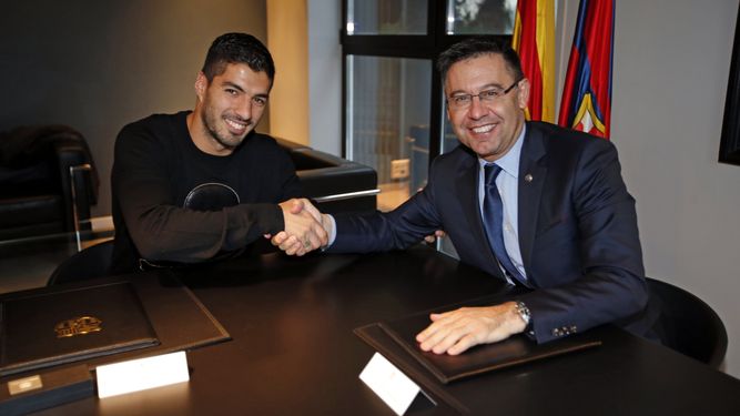 Luis Suárez (izquierda) estrecha la mano del presidente del Barcelona, Josep María Bartomeu (derecha) tras firmar la renovación de su contrato con la entidad azulgrana