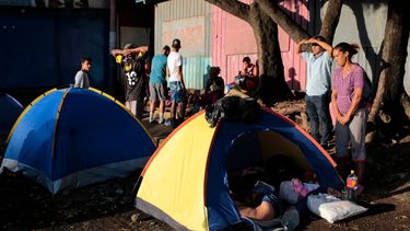 Los migrantes, muchos de ellos venezolanos, se paran junto a sus tiendas mientras esperan para abordar un autobús que los llevará a la frontera entre Nicaragua y Honduras frente a una terminal de autobuses en Managua.