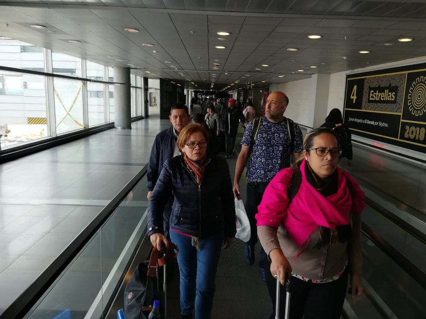 El teniente coronel venezolano Edgar Alejandro Lugo Pereira (2do der.) y sus dos acompañantes, Mildred Josefina Plaza Hernández y Jenny Yamel Rivas González (al frente), son conducidos por un oficial de Migración Colombia en el Aeropuerto Internacional El Dorado, en Bogotá.