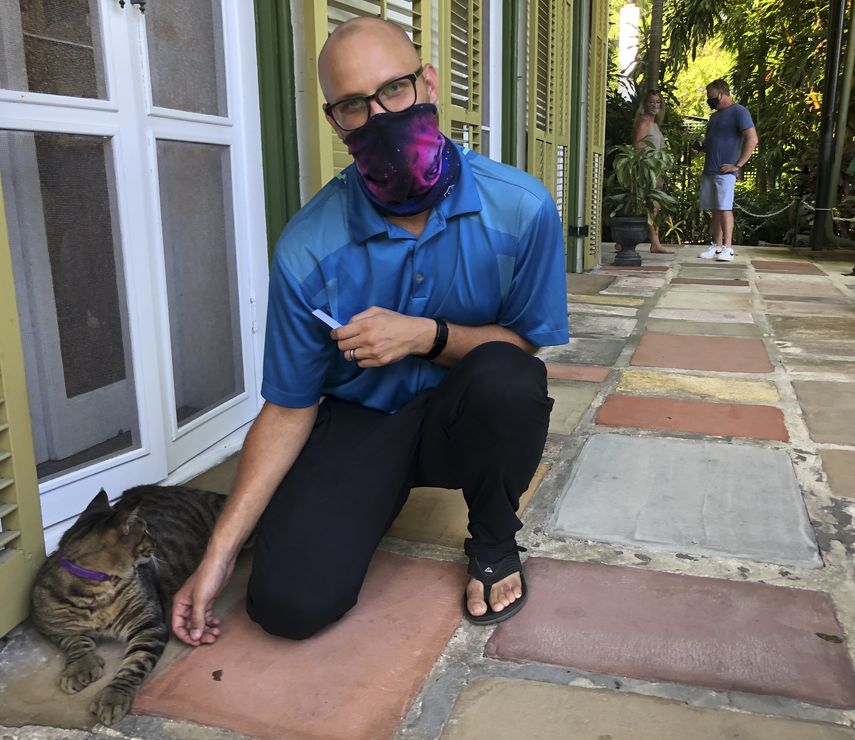 Un turista se tira una foto junto a unos de los gatos que habitan la casa del escritor Ernest Hemingway en Cayo Hueso.