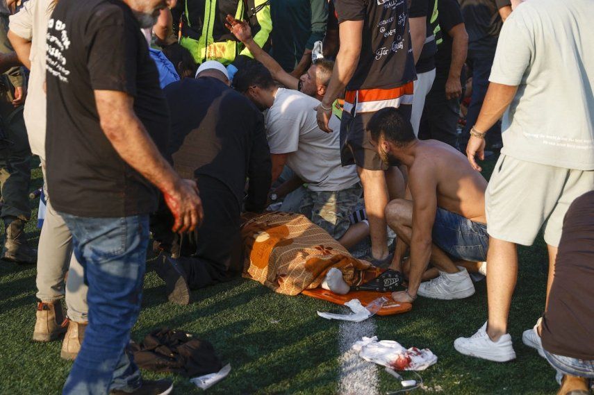 Las fuerzas de seguridad y los médicos israelíes tratan a una víctima mientras los residentes locales se reúnen en un lugar donde se informó de u ataque desde el Líbano en la aldea de Majdal Shams en los Altos de Golán, el 27 de julio de 2024.