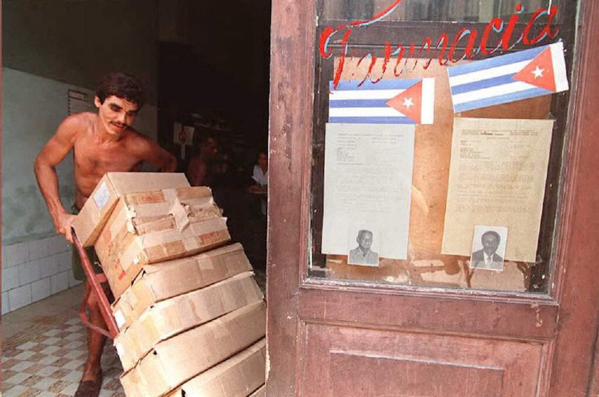 Un cubano manipula cajas en una farmacia local en el centro de La Habana, el 6 de julio de 1995, junto a una vitrina que exhibe fotografías y las biografías de dos candidatos municipales que aspiran a un cargo en las elecciones municipales del 9 de julio.&nbsp;