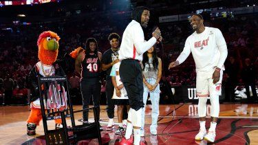 El alero del Heat de Miami, Udonis Haslem, a la izquierda, con el centro Bam Adebayo, a la derecha, mientras le presentan una mecedora durante una ceremonia antes de un partido de baloncesto de la NBA contra el Orlando Magic, el domingo 9 de abril de 2023 en Miami.