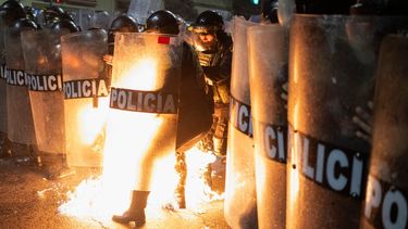 Un agente de la policía antidisturbios es alcanzado por una bomba molotov lanzada por manifestantes durante una manifestación antigubernamental en Lima el 21 de septiembre de 2025.