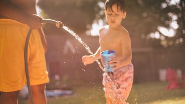 Niños se refrescan en un jardín.&nbsp;