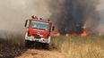 Unos bomberos conducen un camión de bomberos mientras intentan extinguir un incendio forestal en la zona de Veniza, al oeste de Atenas, en la región de Beocia, el 2 de agosto de 2026.