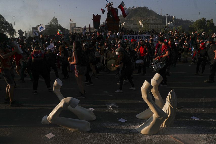 Manifestantes contra el gobierno protestan junto a la instalación de un caballo patas arriba del artista Maireni en Santiago de Chile.