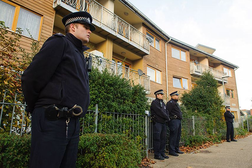 Policías montan guardia afuera de una unidad de departamentos durante las investigaciones casa por casa en una zona donde tres mujeres fueron mantenidas supuestamente como esclavas durante 30 años en una vivienda en el sur de Londres. (AP Fhoto/Dominic