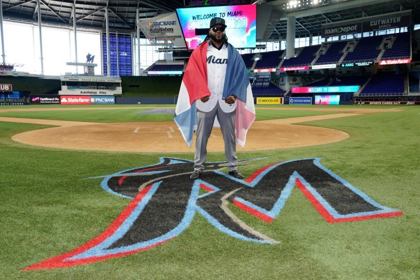 El dominicano Johnny Cueto posa para una foto, envuelto en la bandera de su país y con el jersey de los Marlins de Miami, el jueves 19 de enero de 2023.
