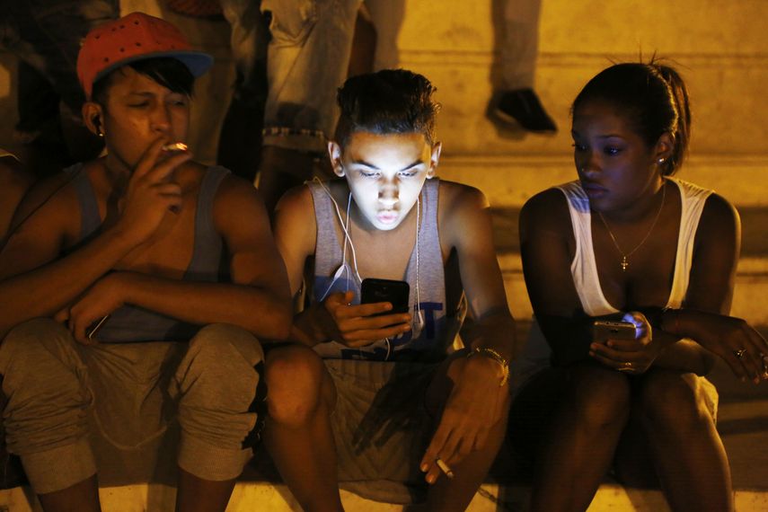 Un grupo de jóvenes consulta la red de Internet en un parque wifi.
