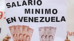 Una mujer sostiene un cartel que muestra el salario mínimo diario aproximado en Venezuela durante una protesta para exigir mejores salarios y pensiones en Caracas el 13 de marzo de 2025. (Foto de Pedro MATTEY / AFP)