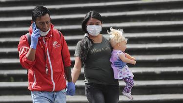 Una pareja con mascarillas y guantes para evitar el contagio del nuevo coronavirus camina de la mano por el centro de Quito, Ecuador, el viernes 10 de abril de 2020.&nbsp;