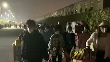 En esta imagen extraída de un video y publicada por Hangpai Xingyang, gente con maletas sale de un complejo de Foxconn en Zhengzhou, en la provincia central china de Henan, el sábado 29 de octubre de 2022. Los trabajadores en una planta de Foxconn en laciudad central china de Zhengzhou parecían haber abandonado el recinto para evitar restricciones asociadas al COVID-19.&nbsp;