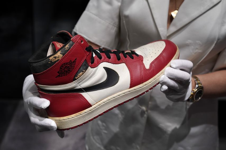 Una mujer muestra una de las zapatillas subastadas de Michael Jordan.