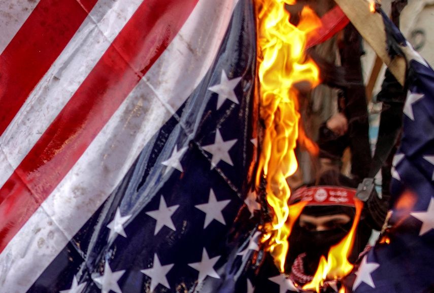 Milicianos palestinos queman una bandera estadounidense durante una protesta en&nbsp;Gaza&nbsp;(Palestina).