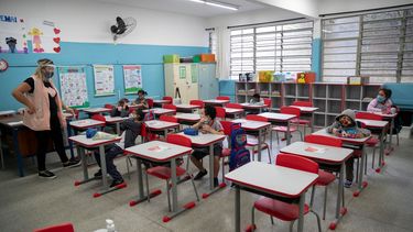 Una maestra trabaja con estudiantes, todos ellos con máscaras, durante el primer día de regreso a clases presenciales en medio de la pandemia de COVID-19 en la escuela pública Raúl Antonio Fragoso en Sao Paulo, Brasil, el lunes 8 de febrero de 2021.