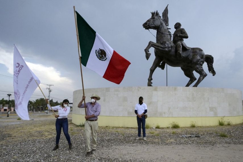 El candidato a alcalde independiente Julio González (C) ondea una bandera nacional mexicana durante un mitin de campaña en Dolores Hidalgo, estado de Guanajuato, México, el 5 de mayo de 2021. La violencia es desenfrenada en la campaña electoral local mexicana con varios candidatos asesinados o amenazados, como Julio González.