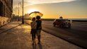 Una pareja con mascarillas para protegerse del nuevo coronavirus sostiene un paraguas mientras camina por el malecón al atardecer en La Habana, Cuba, el lunes 31 de agosto de 2020. Las autoridades de La Habana dispusieron prorrogar la noche del viernes un paquete de medidas restrictivas que incluyen el toque de queda nocturno en la capital mientras tratan de controlar un rebrote de COVID-19. Una pareja con mascarillas para protegerse del nuevo coronavirus sostiene un paraguas mientras camina por el malecón al atardecer en La Habana, Cuba, el lunes 31 de agosto de 2020. Las autoridades de La Habana dispusieron prorrogar la noche del viernes un paquete de medidas restrictivas que incluyen el toque de queda nocturno en la capital mientras tratan de controlar un rebrote de COVID-19.