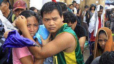 Una pareja protege a su bebe de la lluvia mientras espera un vuelo para ser evacuados en Tacloban el martes 12 de noviembre del 2013. (AP)