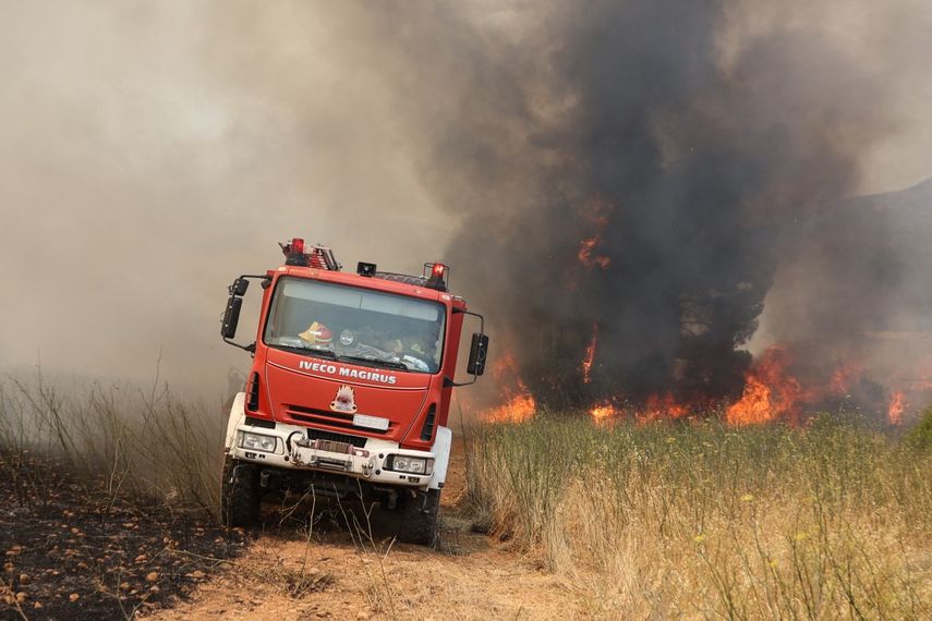 Unos bomberos conducen un camión de bomberos mientras intentan extinguir un incendio forestal en la zona de Veniza, al oeste de Atenas, en la región de Beocia, el 2 de agosto de 2026.