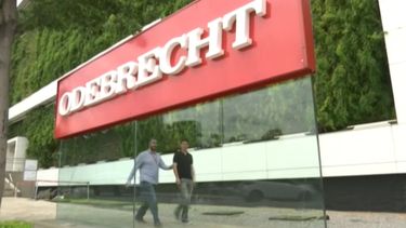 Dos hombres caminan frente al logo de la constructora brasileña Odebrecht.