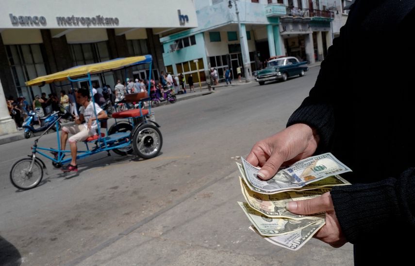 Una persona muestra dólares estadounidenses frente a un banco en La Habana, Cuba.&nbsp;