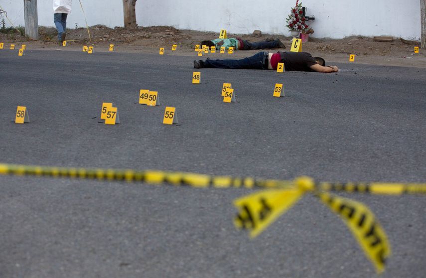 En esta foto de archivo del 29 de junio de 2017, los investigadores marcan el lugar donde cayeron las balas junto a varios cuerpos que yacen en una carretera en la ciudad de Navolato, estado de Sinaloa, M&eacute;xico. Para las personas en pueblos y aldeas mexicanas donde las pandillas criminales, los grupos armados y los narcotraficantes tienen m&aacute;s influencia que el Estado, el nuevo coronavirus es el &uacute;ltimo peligro. La amenaza de muerte y la incapacidad de moverse libremente no son nada nuevo.