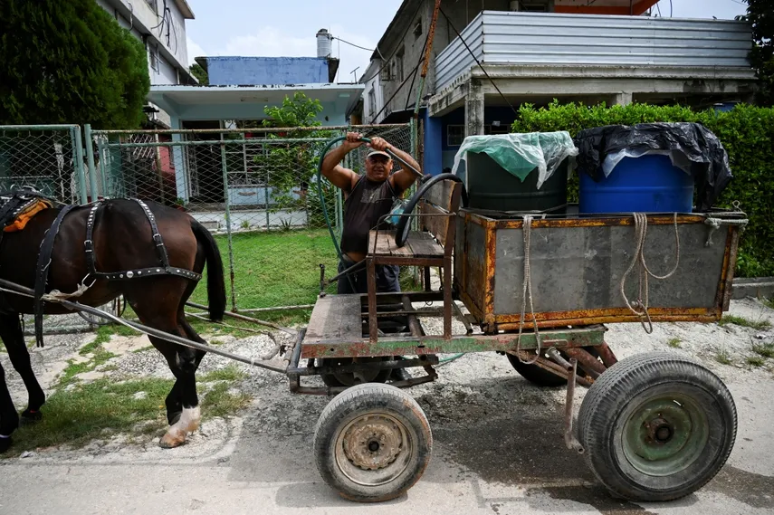 Un hombre se prepara para descargar agua de un bidón de plástico desde su carro tirado por caballos en La Habana, el 24 de septiembre de 2024.