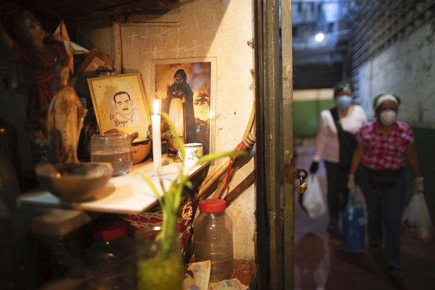 En esta foto del 20 de marzo de 2020, una vela ilumina un altar en un puesto de hierbas en un mercado en Caracas, Venezuela.&nbsp;
