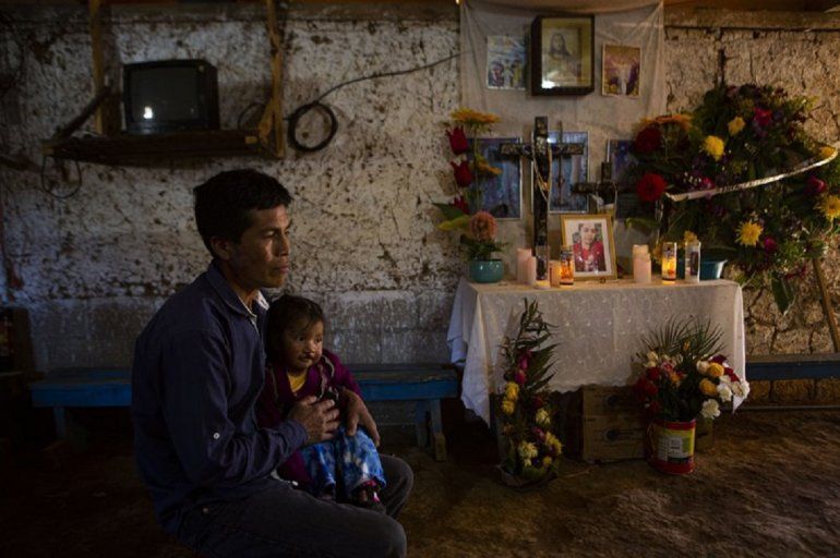 Ricardo García y su hija Ángela, sentados junto a un altar adornado con fotografías de su hija mayor, Santa García, en su casa en Comitancillo, Guatemala, el 27 de enero de 2021. García cree que el cuerpo de Santa es uno de los cadáveres calcinados hallados en un estado del norte de México.