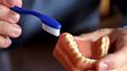 Un dentista sostiene un modelo dental y un cepillo de dientes en Seattle, el 3 de agosto de 2018.