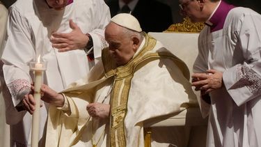 El papa Francisco sostiene un cirio al presidir un oficio de vigilia pascual en la Basílica de San Pedro.