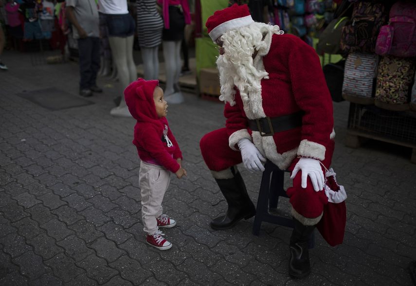 Fredy Parra, vestido de Santa Claus, habla con una niña en una feria navideña en Caracas, Venezuela, el viernes 18 de diciembre de 2020.&nbsp;