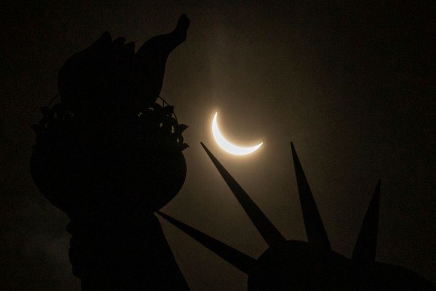 La luna cubre parcialmente el sol sobre la Estatua de la Libertad durante el eclipse solar visto desde la Isla de la Libertad, el lunes de abril. 8 de enero de 2024 en Nueva York.