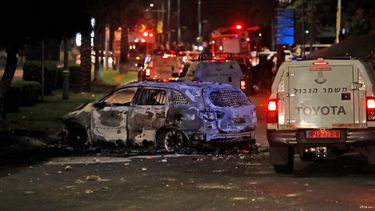Los vehículos de la policía fronteriza israelí pasan frente a un vehículo quemado extinguido en Lod, cerca de Tel Aviv, el 11 de mayo de 2021, después de que Hamas lanzó cohetes hacia Israel desde la Franja de Gaza controlada por Hamas.