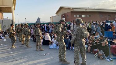 Soldados estadounidenses montan guardia mientras los afganos esperan abordar un avión militar estadounidense para salir de Afganistán, en el aeropuerto militar de Kabul el 19 de agosto de 2021 después de la toma militar de Afganistán por los talibanes.
