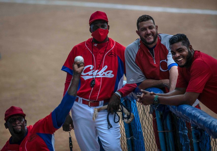 El pitcher Yoanni Yera Montalvo (izquierda), hace un lanzamiento durante una práctica de la selección de Cuba mientras varios de sus compañeros sonríen, el martes 18 de mayo de 2021, en el Estadio Latinoamericano de La Habana&nbsp;