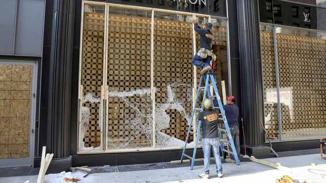 Trabajadores cubren con tablones la vidriera de una tienda de la cadena Louis Vuitton en la ciudad de Chicago. &nbsp; &nbsp;