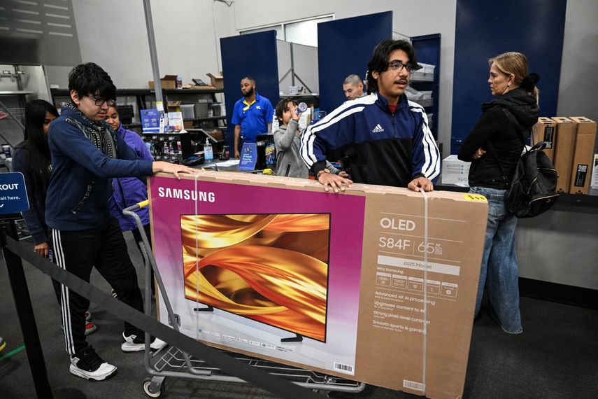 Varias personas trasladan un televisor durante las compras de viernes negro.