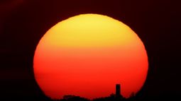 En esta fotografía de archivo del viernes 26 de junio de 2020, se ve a la distancia la puesta del sol atrás de una chimenea en Kansas City, Missouri.&nbsp;