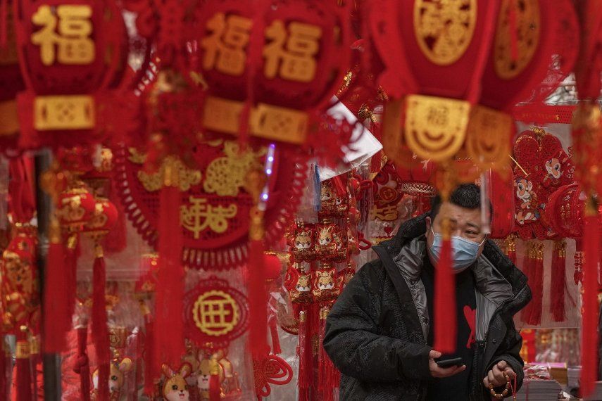 Un hombre, con mascarilla para protegerse del coronavirus, compra decoraciones para el Año Nuevo Lunar en un puesto en Beijing, el 7 de enero de 2023.&nbsp;&nbsp;