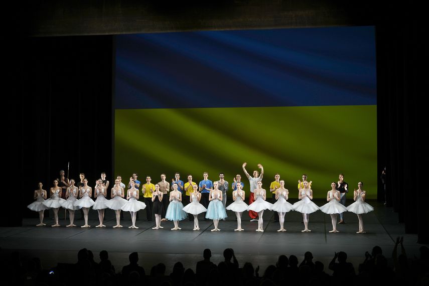 Bailarines del Ballet de la Ciudad de Kiev reciben el aplauso del público delante de una bandera de Ucrania proyectada en una pantalla, en el Theatre de Chatelet, en París.