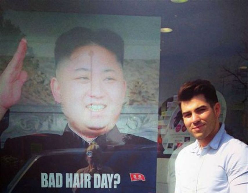 Estilista londinense Karim Nabbach frente a un cartel con el retrato del líder norcoreano Kim Jong-un y su inusual corte de cabello (Foto: AP)