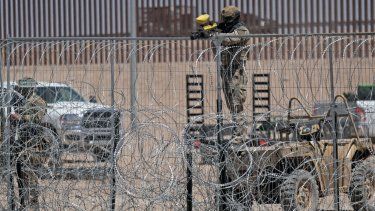 Un miembro de la Guardia Nacional de Texas custodia la frontera con un arma de perdigones de gas mientras centenares de migrantes se manifiestan en el río Grande para pedir autorización para ingresar a Estados Unidos, el 25 de abril de 2024.