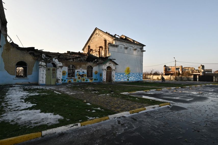 La gente pasa frente a una casa de la cultura muy dañada en Irpin, al noroeste de Kyiv, el 23 de diciembre de 2022, en medio de la invasión rusa de Ucrania. La Biblioteca de Irpin salió prácticamente indemne de los intensos combates de la guerra.