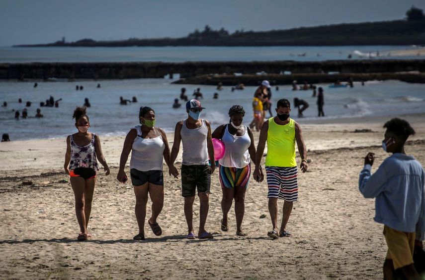 Personas que usan m&aacute;scaras como precauci&oacute;n contra la propagaci&oacute;n del nuevo coronavirus caminan en la playa en La Habana, Cuba, el domingo 11 de octubre de 2020.&nbsp;